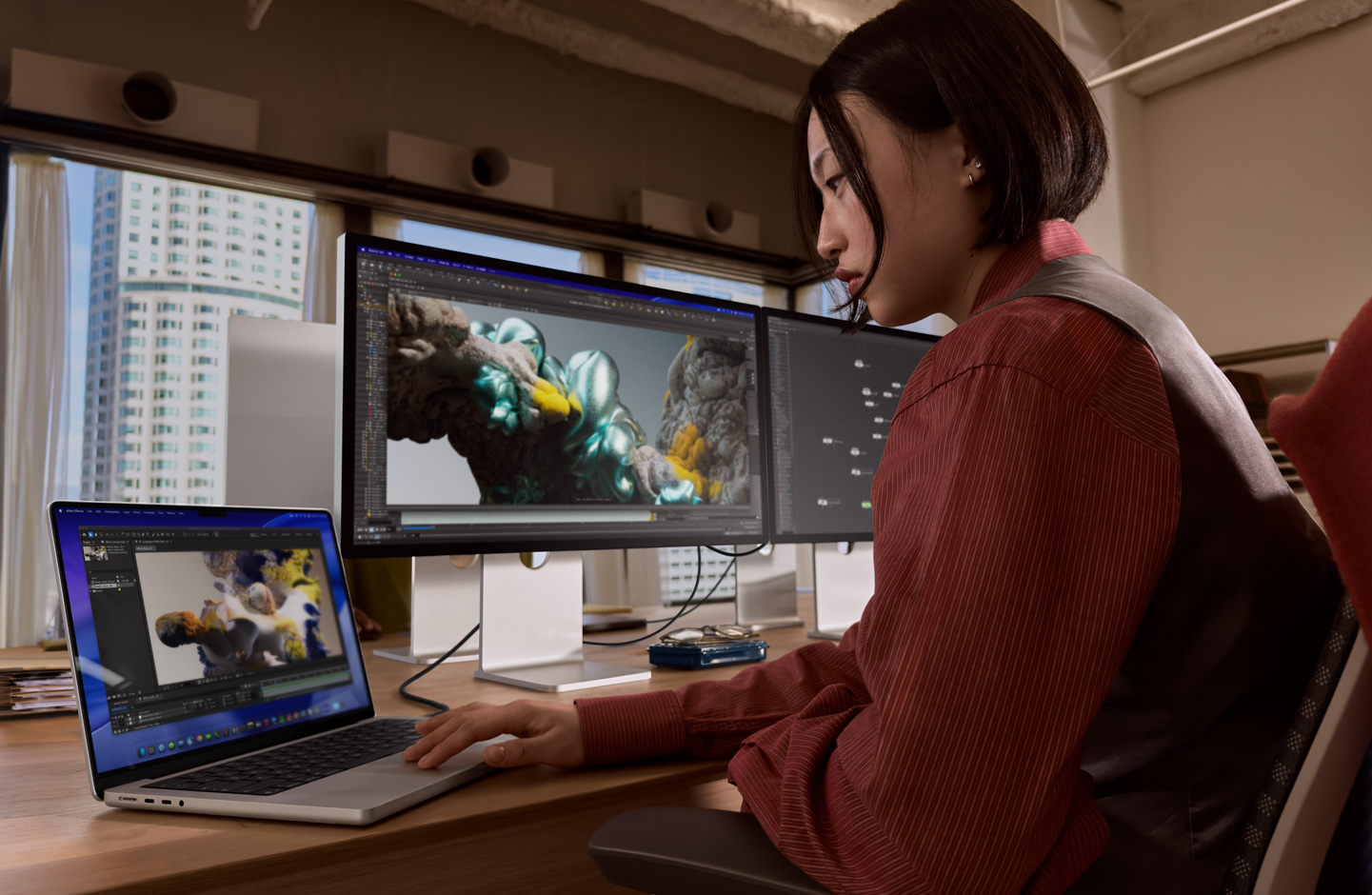 一個人在辦公環境中，使用 MacBook 手提電腦工作，MacBook 透過 Thunderbolt 5 連接埠連接至 Studio Display XDR